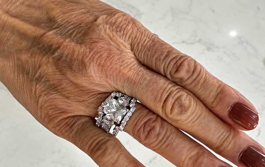 White sapphire three-piece wedding set worn on a hand